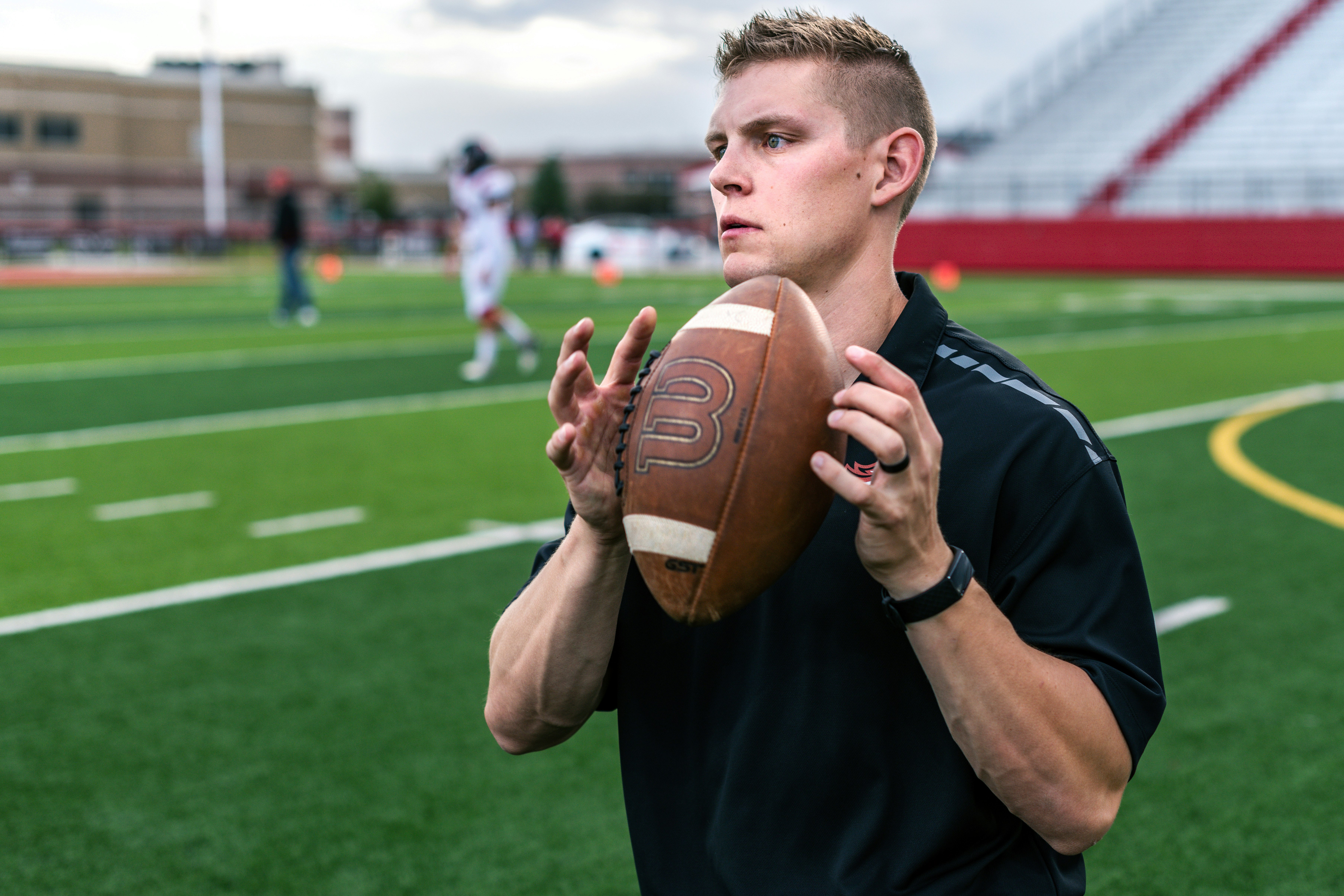 man in black crew neck t-shirt holding brown football